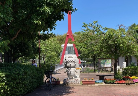 大阪狭山市市民ふれあいの里入り口に立つ狭山市マスコットさやりんの石像と赤い鉄橋