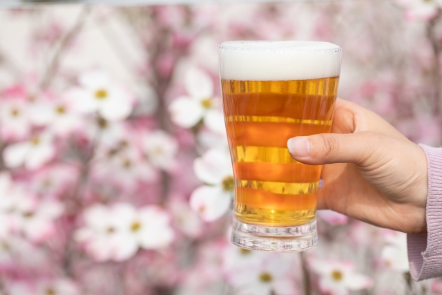 桜の背景にビールを持つ片手